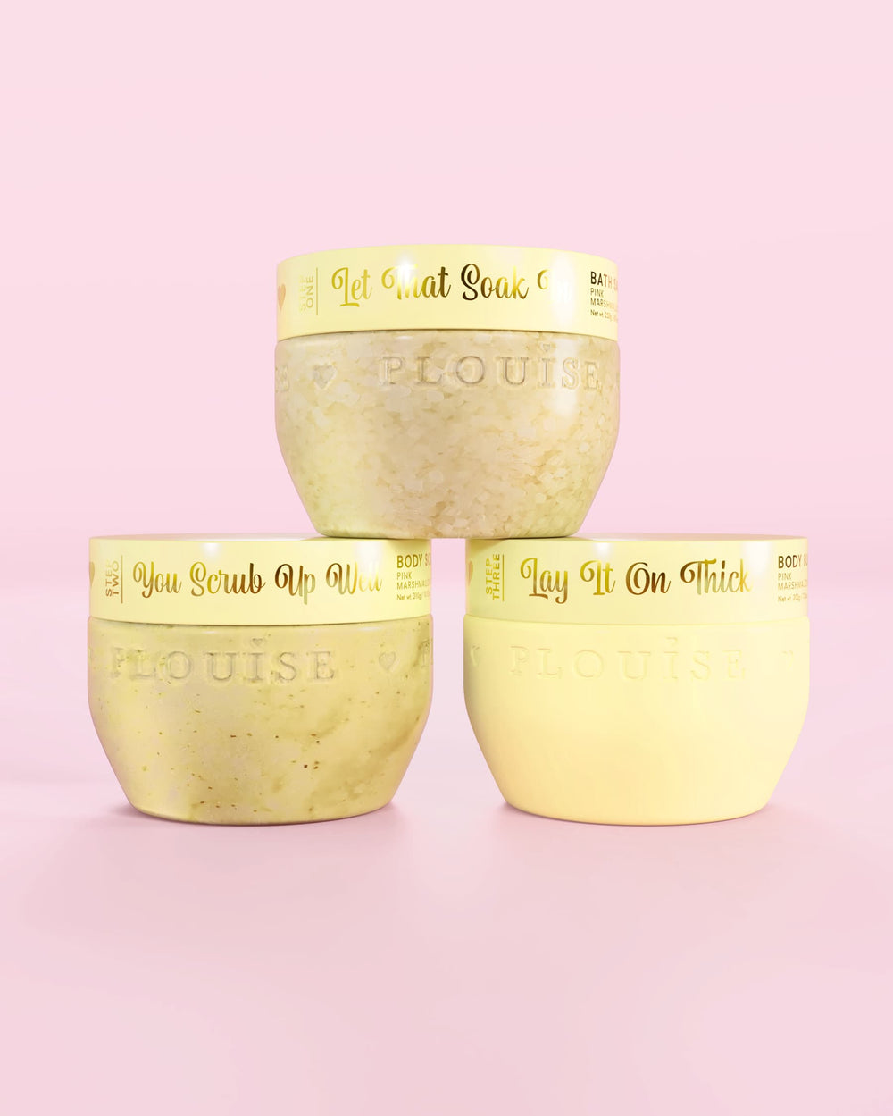 Τρία κίτρινα δοχεία P.Louise Hop Into Self-Care Starwberry Shortcake με άλατα μπάνιου, απολέπιση σώματος και βούτυρο σώματος με χρυσό κείμενο σε ροζ φόντο
