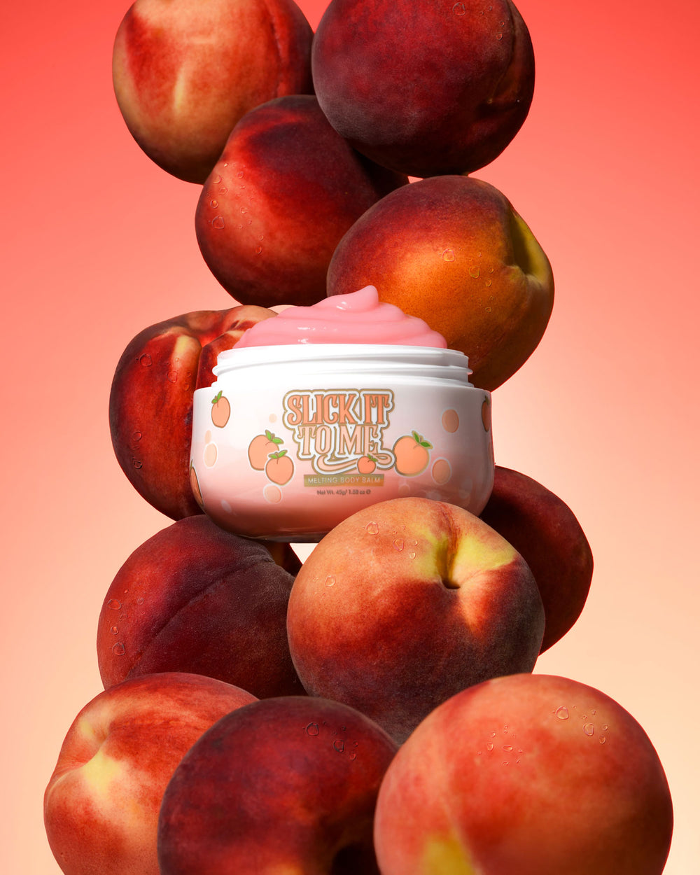 Βάζο P. Louise Slick It To Me Peach Melting Body Balm με ροζ κρέμα που περιβάλλεται από ροδάκινα σε ντεγκραντέ φόντο