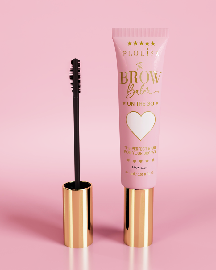 P.Louise Fluffy Soap Brow Balm Instant Fix προϊόν σε ροζ σωληνάριο με χρυσό καπάκι, συνοδευόμενο από μαύρο βουρτσάκι για τα φρύδια, σε ροζ φόντο.
