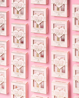 A repeating pattern of pink and white P.Louise 'The Lip Check' lip kits arranged in a grid on a solid pink background.