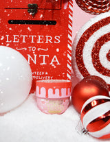 Ένα βάζο P.Louise Lay It On Thick Body Butter σε παραλλαγή Frosted Peppermint, που εκτίθεται με διακοσμητικά με γιορτινό θέμα γύρω του, όπως χριστουγεννιάτικα φωτάκια και δώρα.