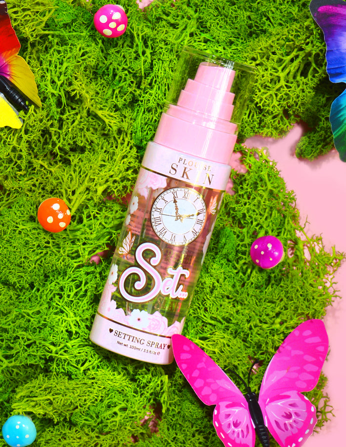 Ένα μπουκάλι P. Louise Ready Set Slay Long Lasting Setting Spray που περιβάλλεται από διακοσμητικά στοιχεία όπως πολύχρωμα ψεύτικα βρύα, πεταλούδες και μανιτάρια.