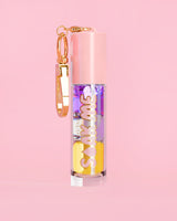 P. Louise Soak Me Lip Oil με πολύχρωμο λαδάκι σε ροζ σωλήνα με χρυσό κούμπωμα σε ροζ φόντο