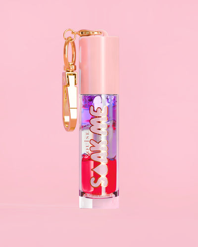 P. Louise Soak Me Lip Oil με πολύχρωμο λαδάκι σε ροζ σωλήνα με χρυσό κούμπωμα σε ροζ φόντο